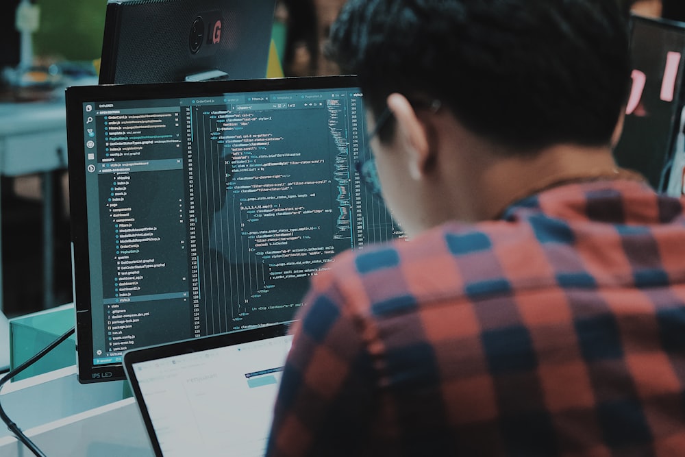 Software developer working at a desk with code on screen